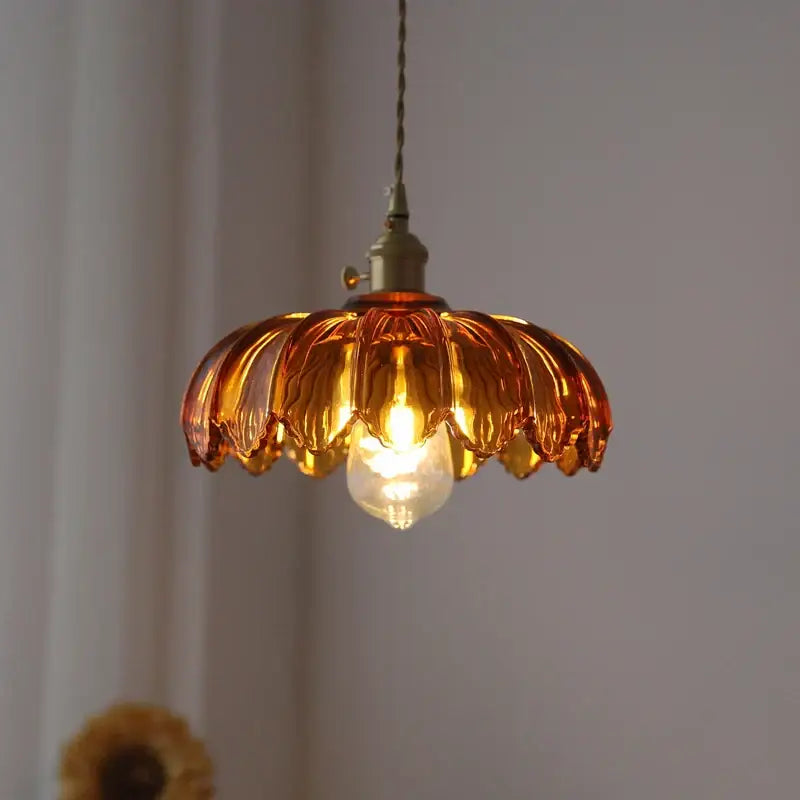 Amber-colored petal glass pendant light with brass hardware in a decorbites glass industrial style for dining room use