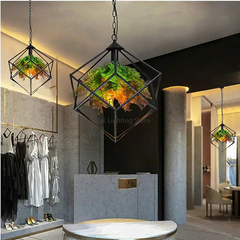 Black metal industrial greenery chandelier featuring a geometric pendant light with hanging green ferns by decorbites industrial
