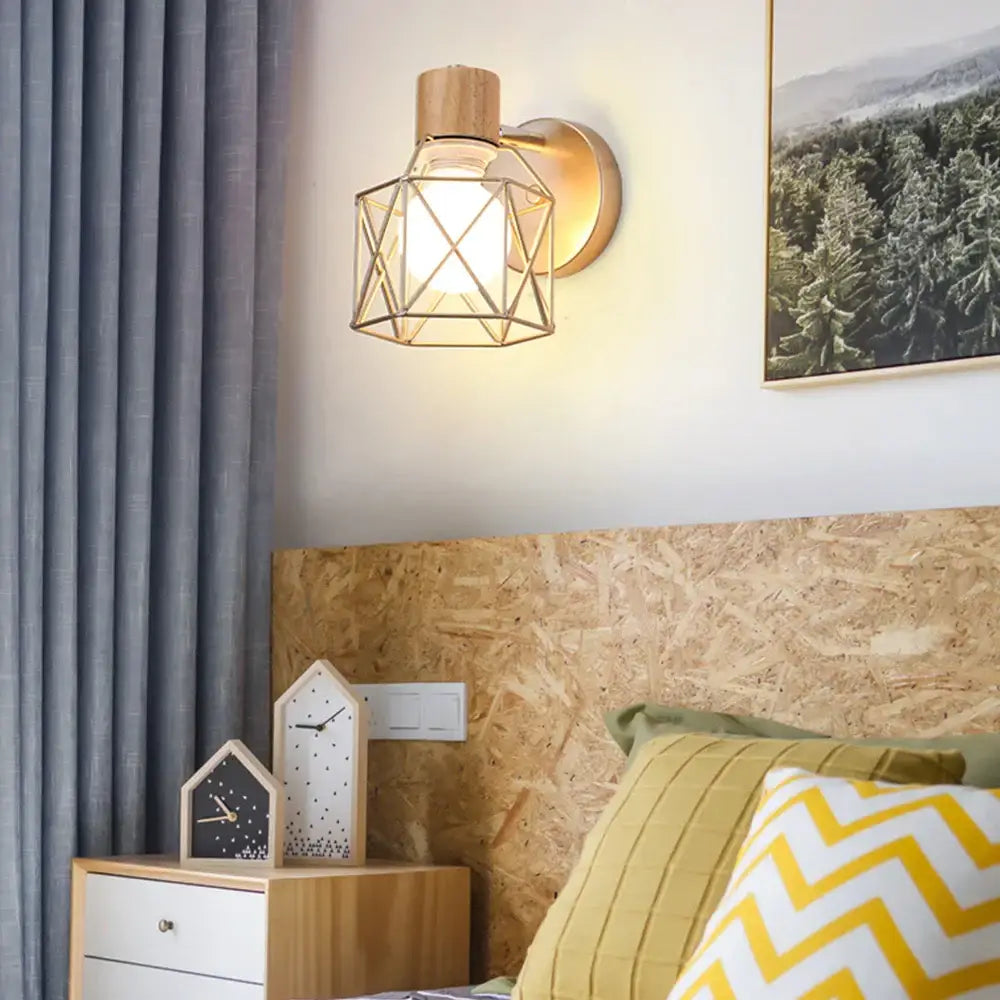 Industrial iron cage wall light with geometric gold-toned metal, wooden top, and clear glass shade for bedroom decorbites iron cage