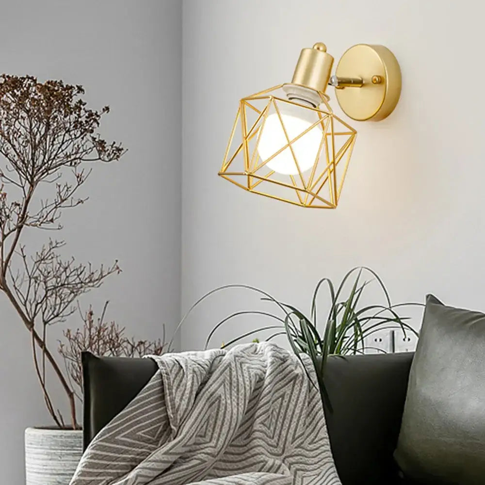 Gold-toned iron cage wall light with faceted geometric design and exposed bulb for industrial decorbites iron cage style