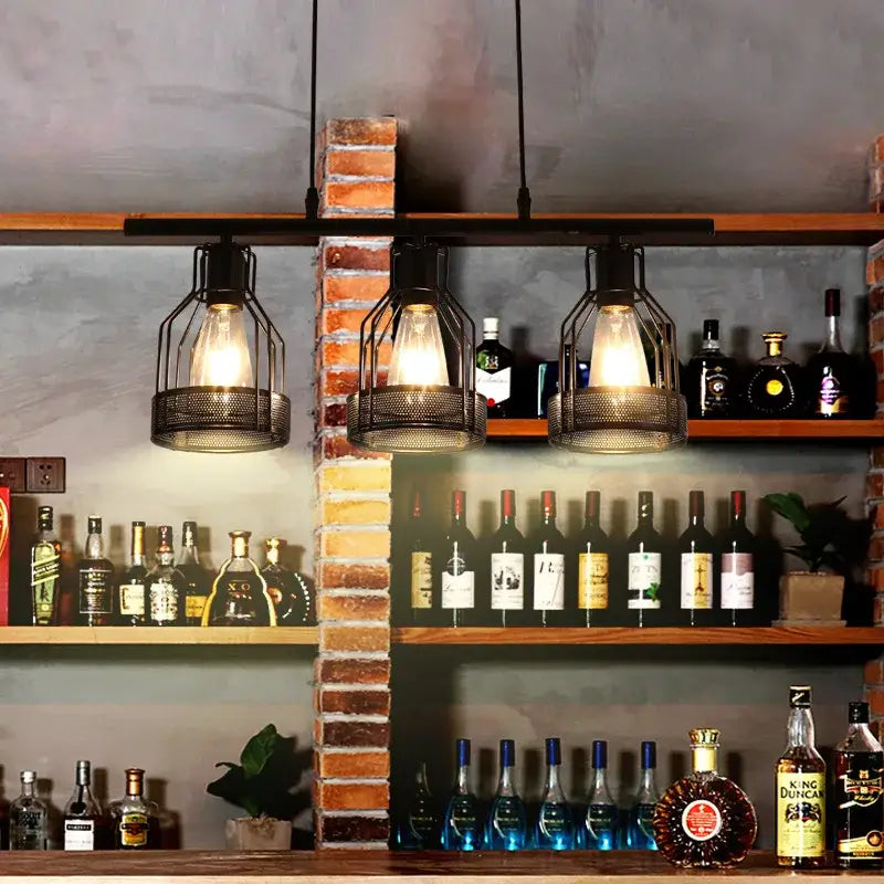 Three black mesh metal cage pendant lights with exposed bulbs hang above a bar in decorbites industrial loft chandelier