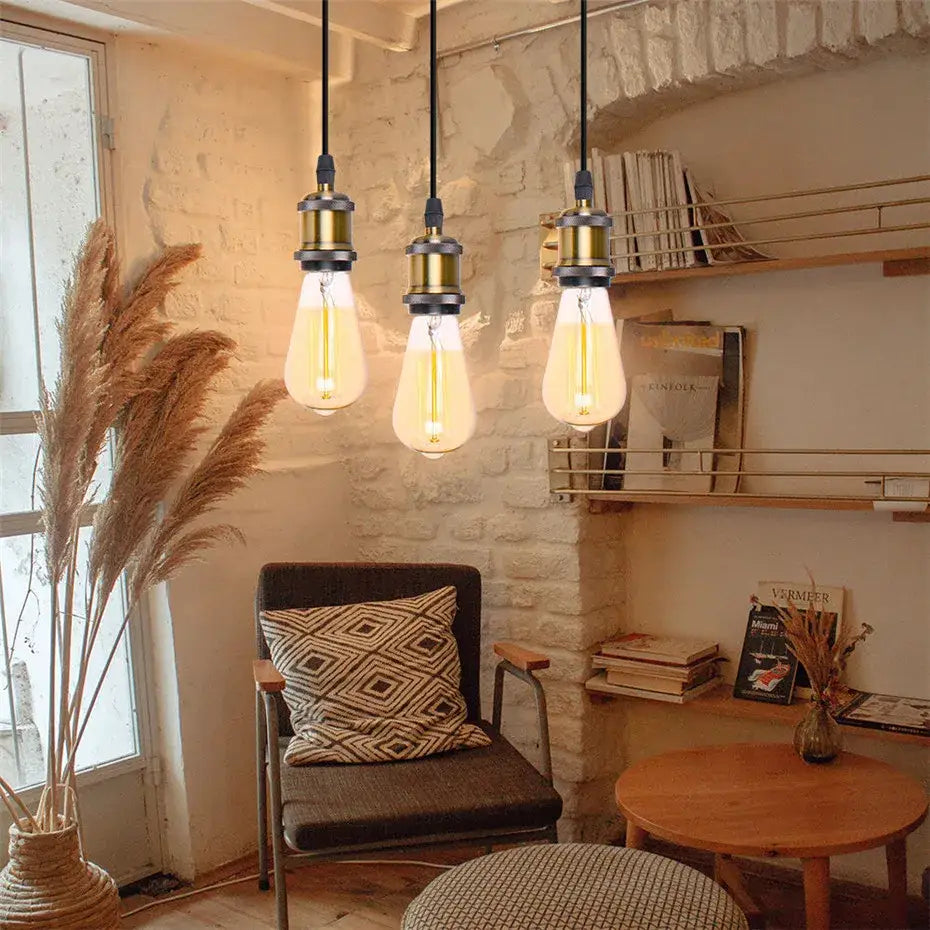 Three vintage-style brass pendant lights with glowing Edison bulbs hang from black cords decorbites industrial loft led