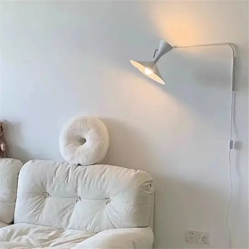 A sleek industrial matte black wall sconce lamp with an adjustable arm designed for bedroom use