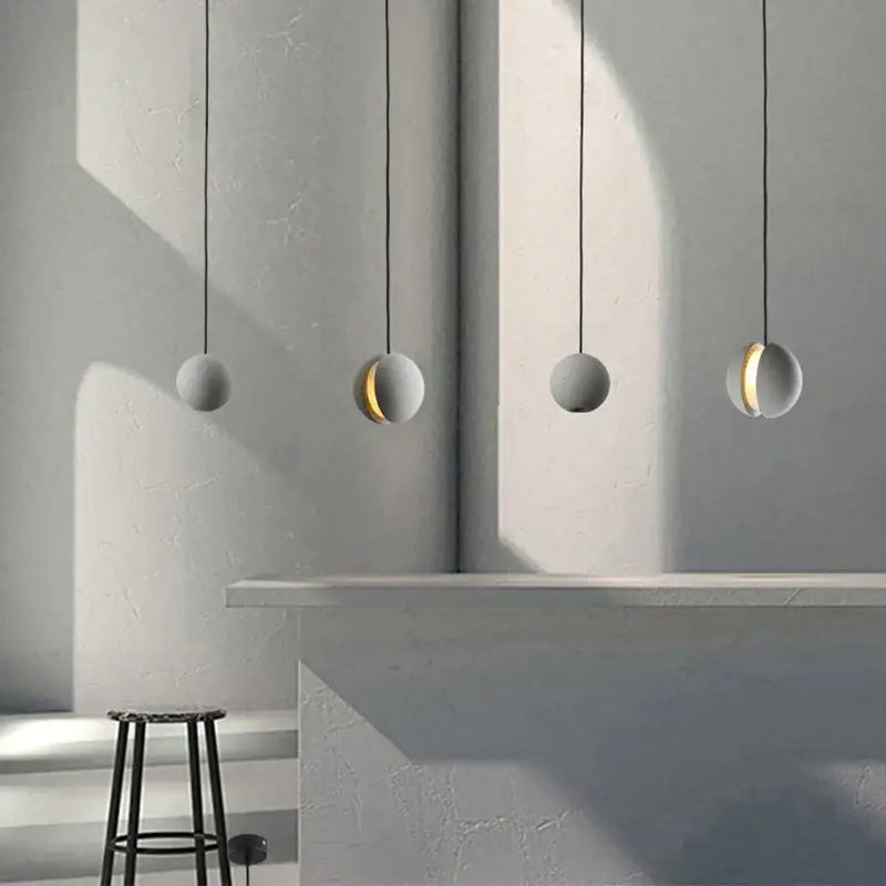 Four minimalist spherical pendant lamps with matte gray cement and gold inner glow by decorbites cement chandelier