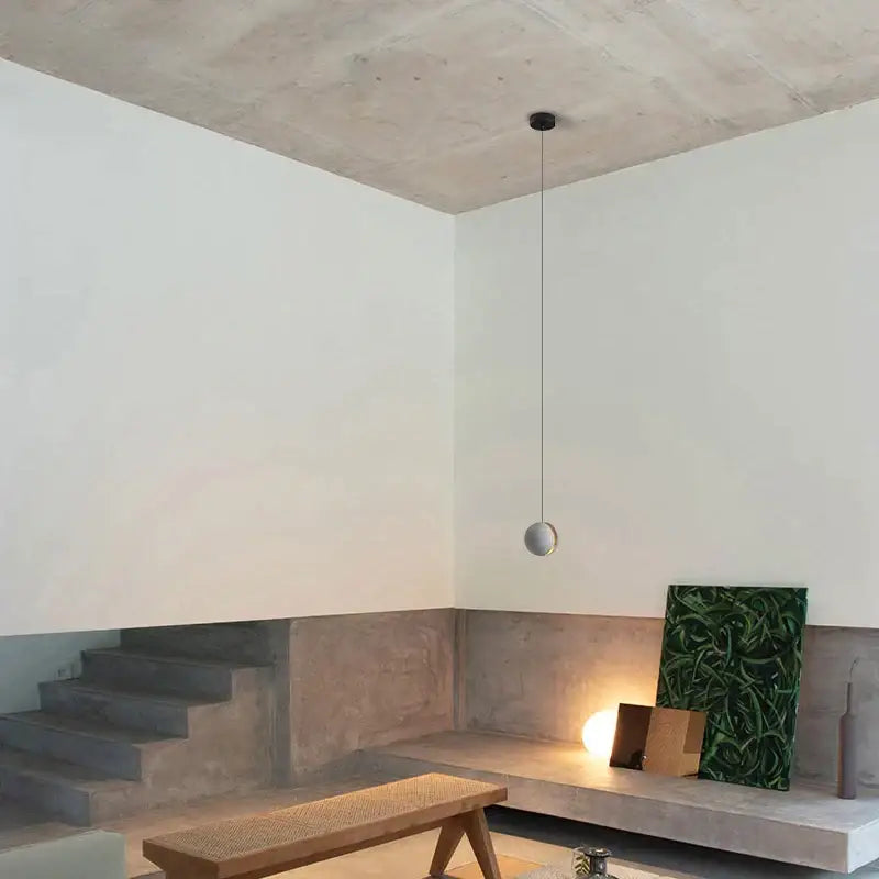 Minimalist spherical pendant lamp with matte metallic finish hanging from thin cord for industrial kitchen decorbites cement chandelier