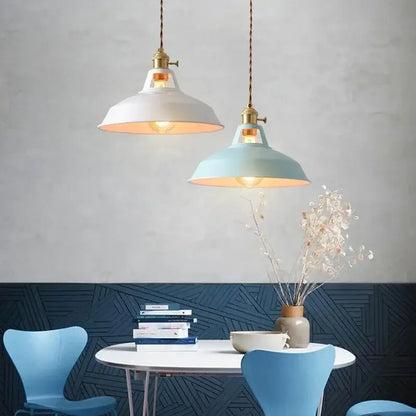 Two pastel metal pendant lights with white and light blue enamel shades metal finish and brass hardware for kitchen use