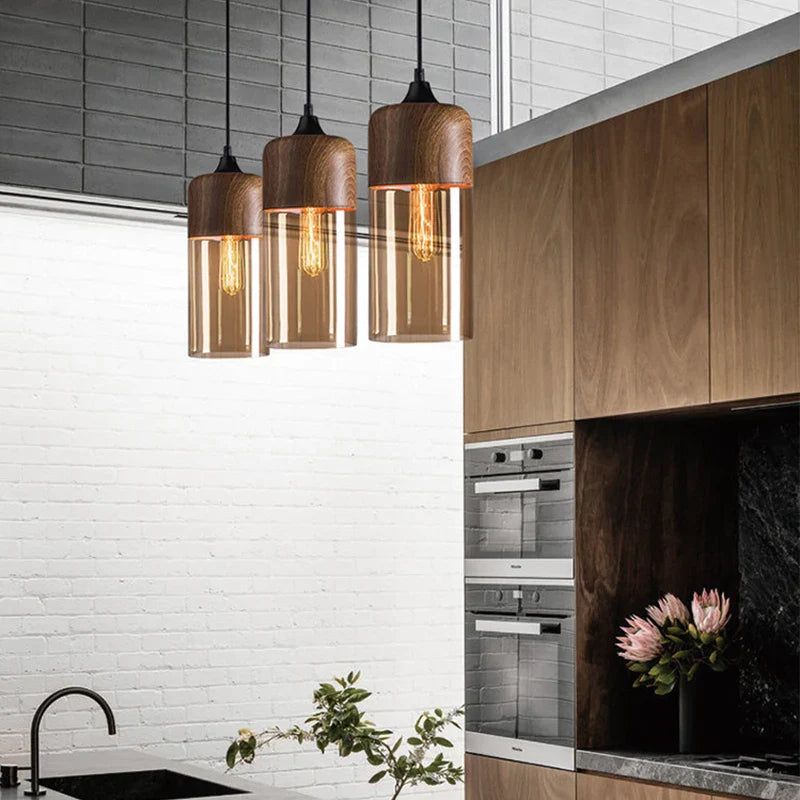 Three modern industrial retro led pendant lights with wooden tops and amber glass shades hang above a dining room counter