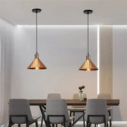 Two copper hammered finish industrial retro pendant lamps with black cords hang above a dining table decorbites industrial retro