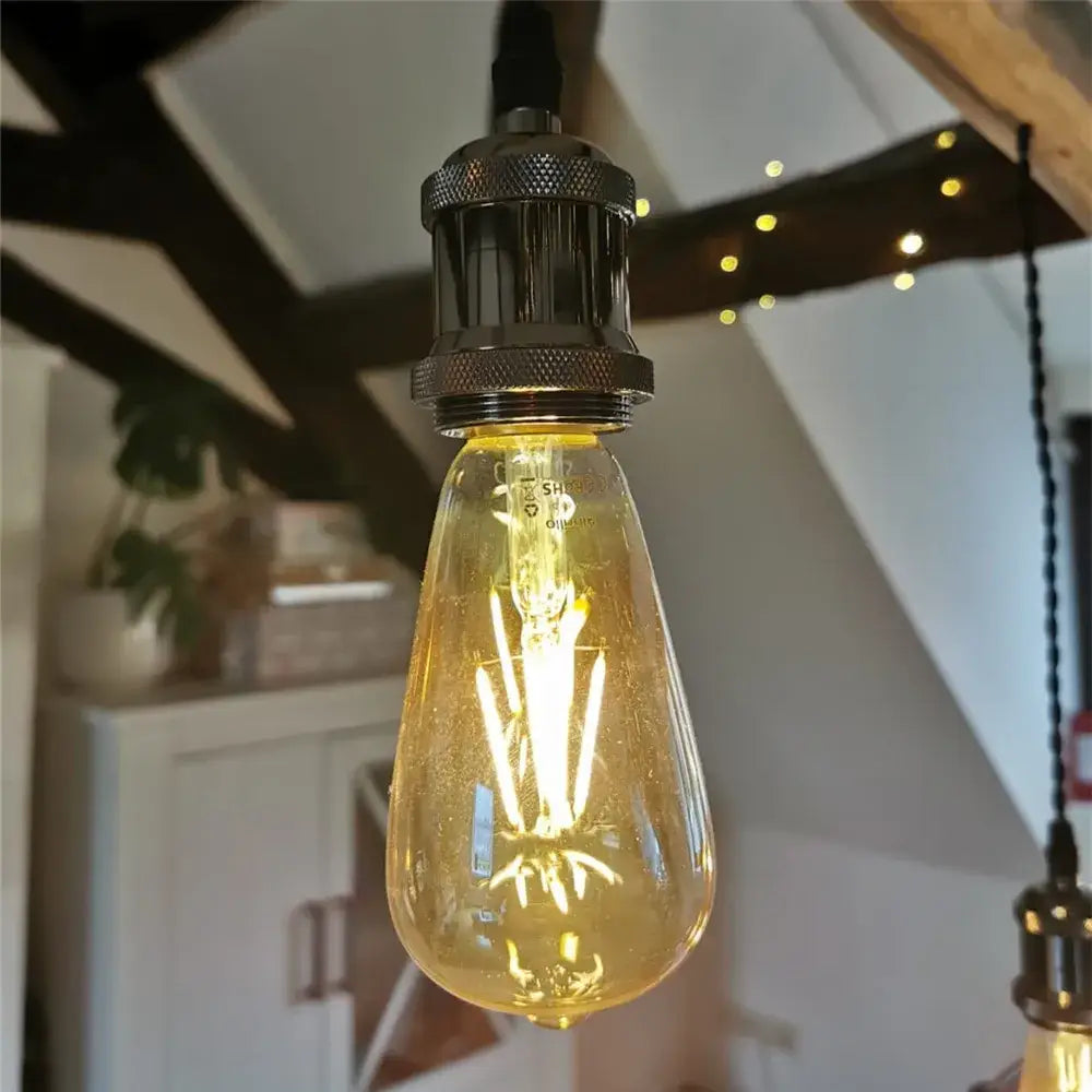 A warm amber glass edison bulb with a textured black metal base in industrial e27 screw decorbites lamp holder pack