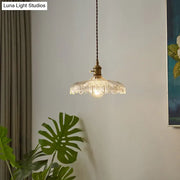 A delicate clear glass scalloped edge pendant ceiling light with brass hardware ideal for industrial restaurant decor