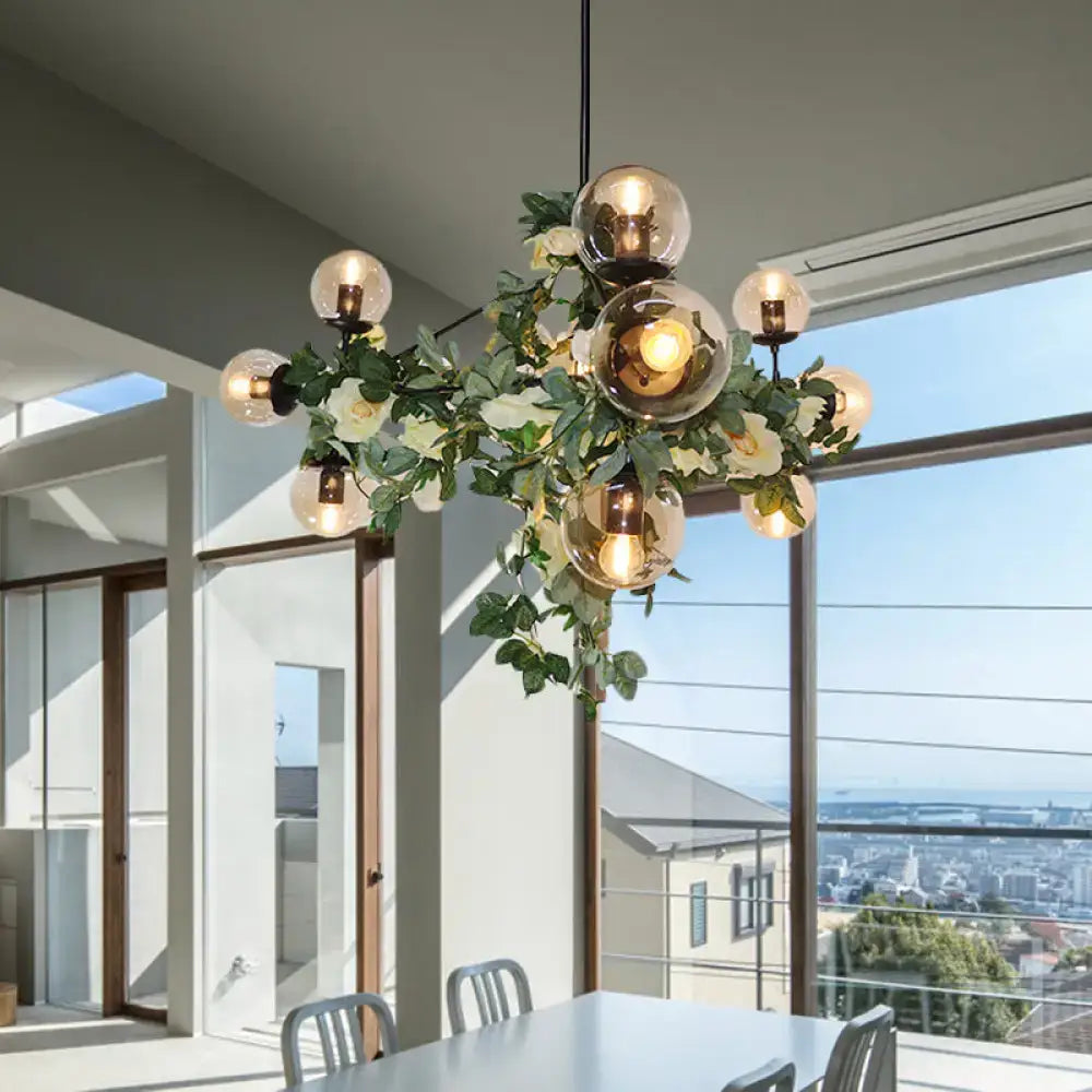 A modern industrial island pendant with smoke gray glass globes and a decorative green vine wreath hanging light