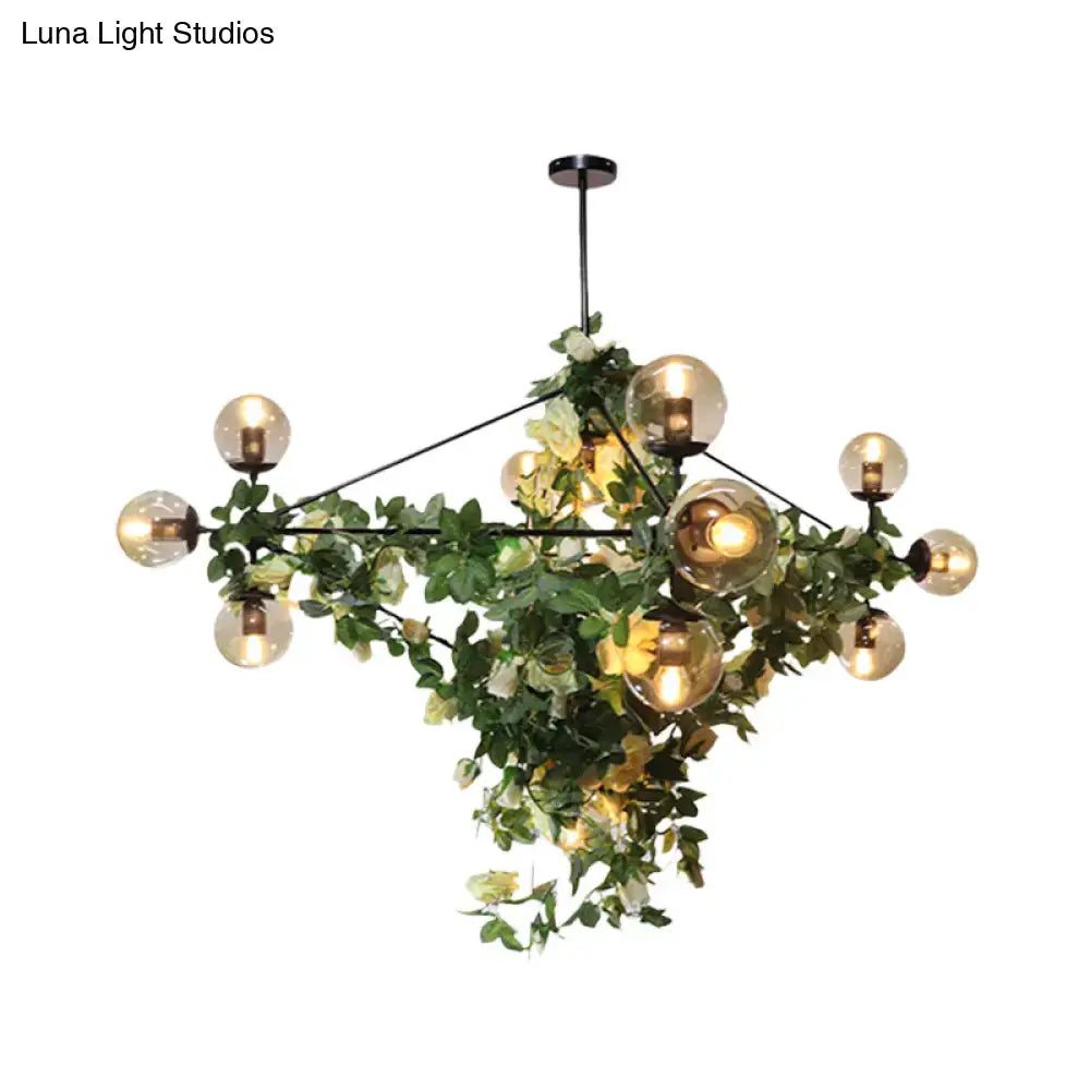 A modern decorbites™ island pendant with black metal frame, smoke gray glass globes, and green white artificial vines