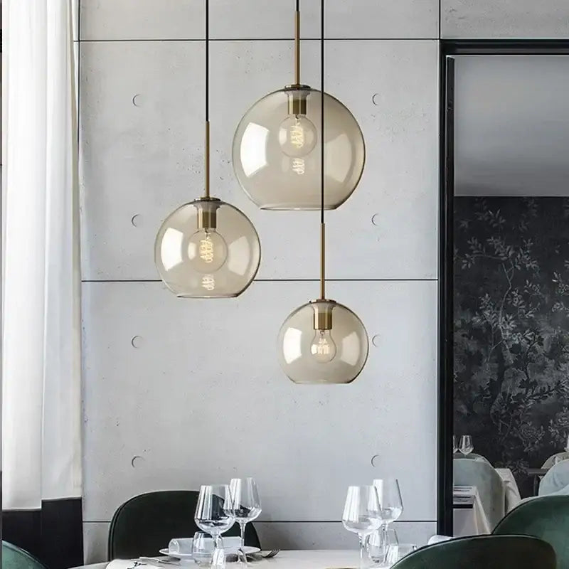 Three spherical industrial glass pendant lights with brass accents hang in a modern dining room decorbites industrial glass