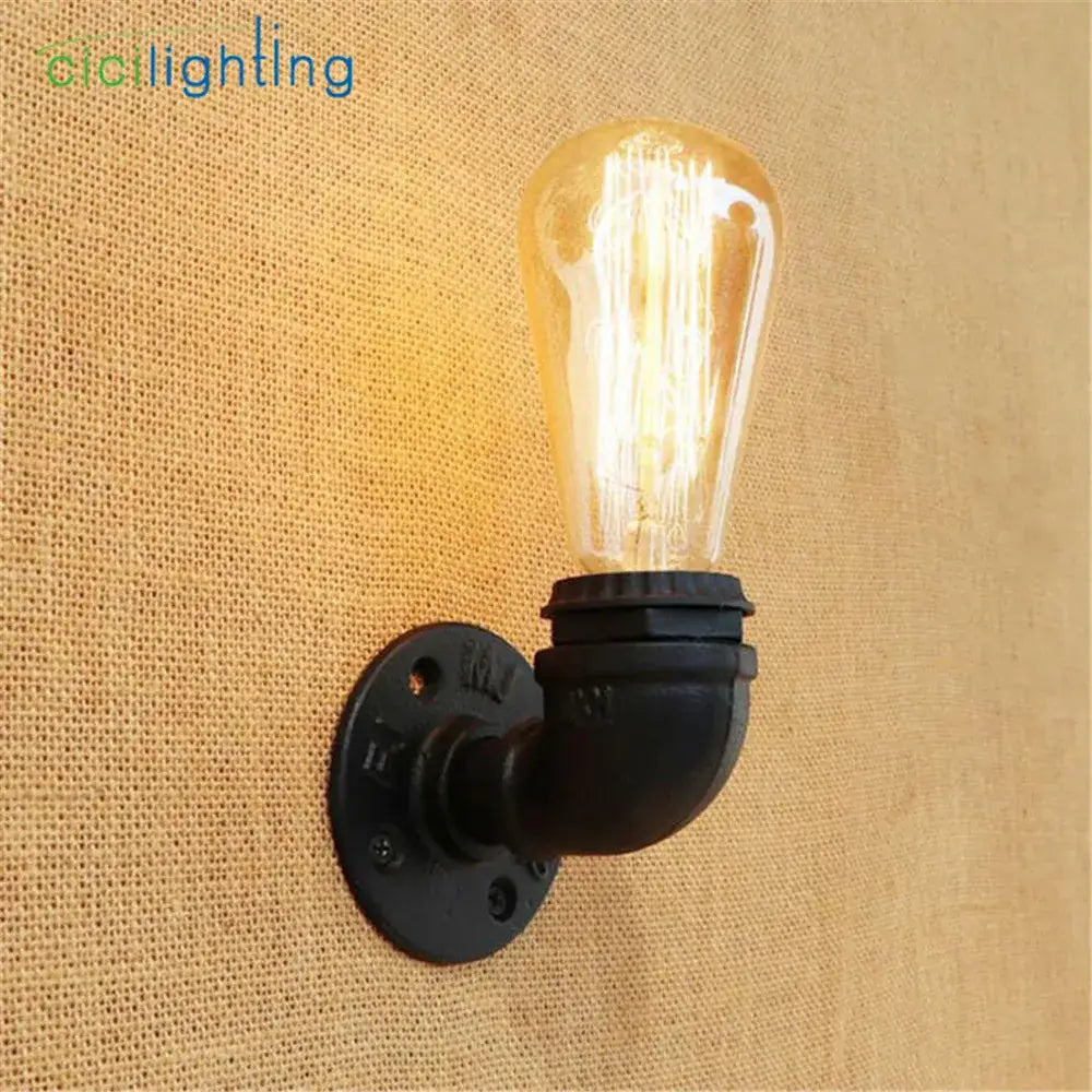 Industrial steampunk loft pipe wall lamp with black pipe and aged brass finish featuring a warm amber filament bulb
