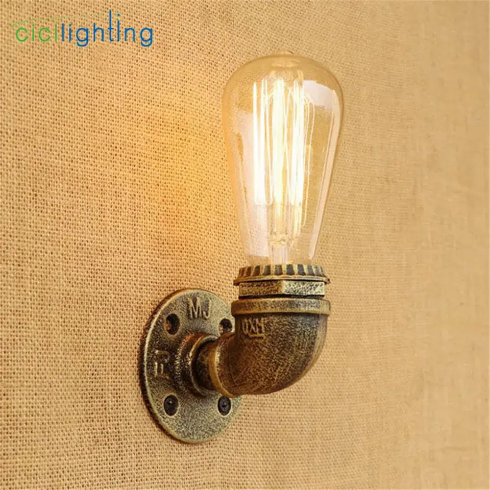 Industrial steampunk loft pipe wall lamp with black and aged brass finish holding an illuminated Edison bulb