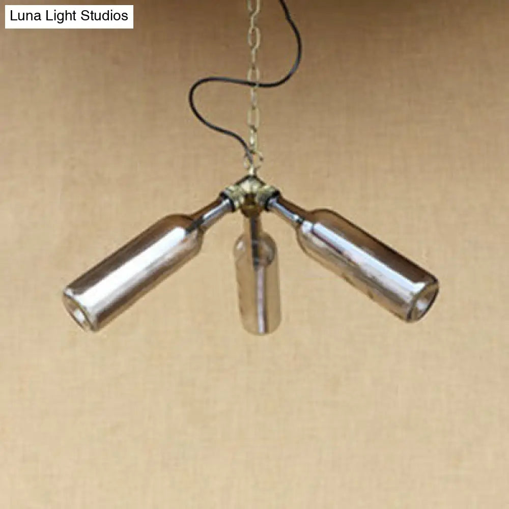 Lámpara de araña de estilo industrial con tres luces, hecha con botellas de vidrio y diseño de tuberías, en negro y transparente.