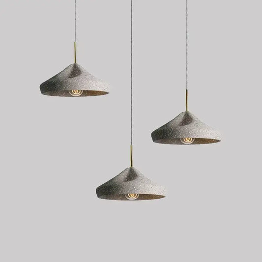 Three modern concrete pendant chandelier lights with speckled gray finish and brass accents industrial style decorbites