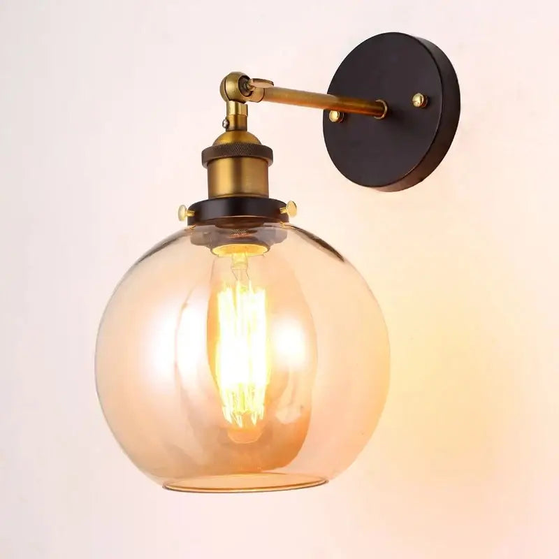 Warm-toned amber glass globe wall lamp with brass accents and black wall plate decorbites industrial vintage loft style