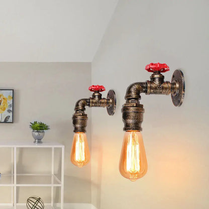 Industrial water pipe wall sconce kitchen light with brass finished pipes red valve handles and glowing amber edison bulbs