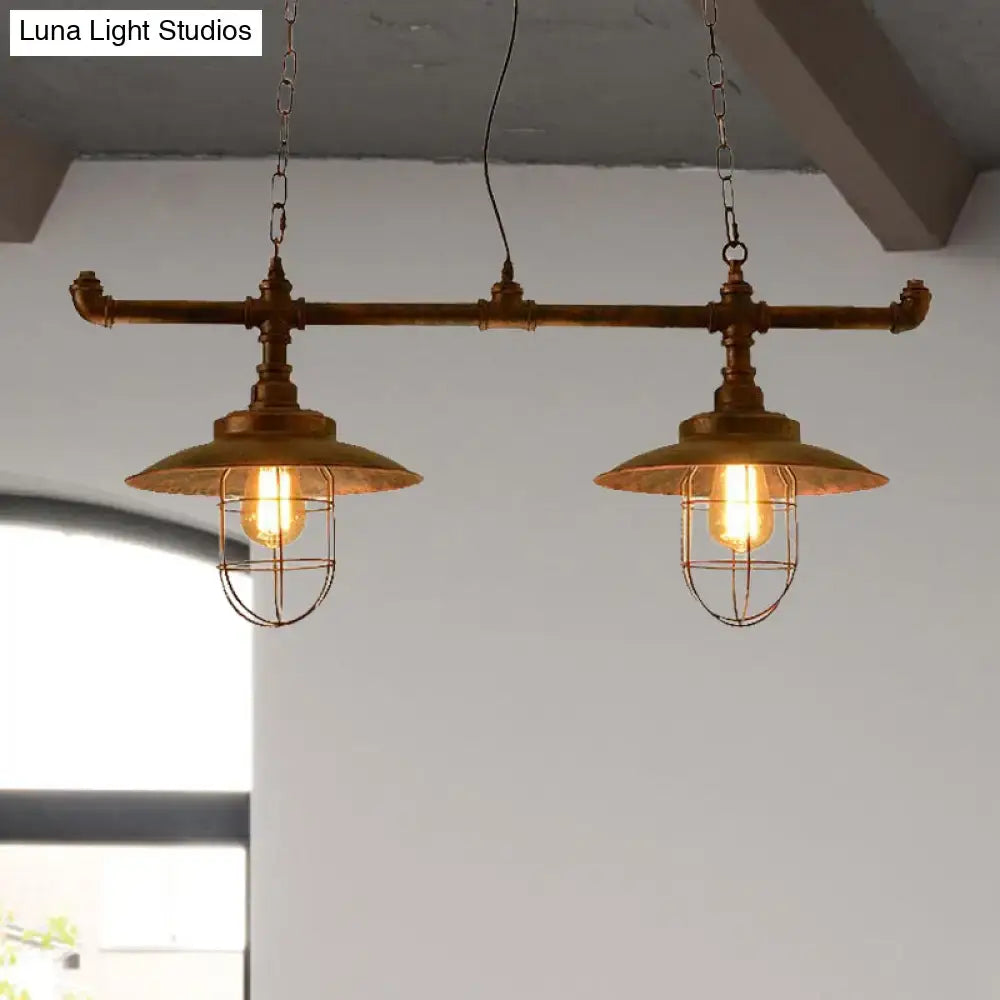Industrial-style brass pendant light with two exposed filament bulbs in weathered copper wire cages suspended by chain cord length