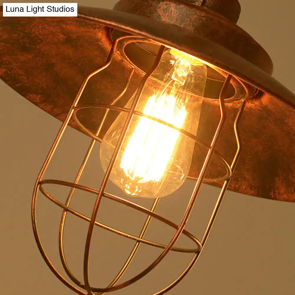 Rustic copper industrial pendant light with wire cage and glowing filament bulb in weathered copper pipe design