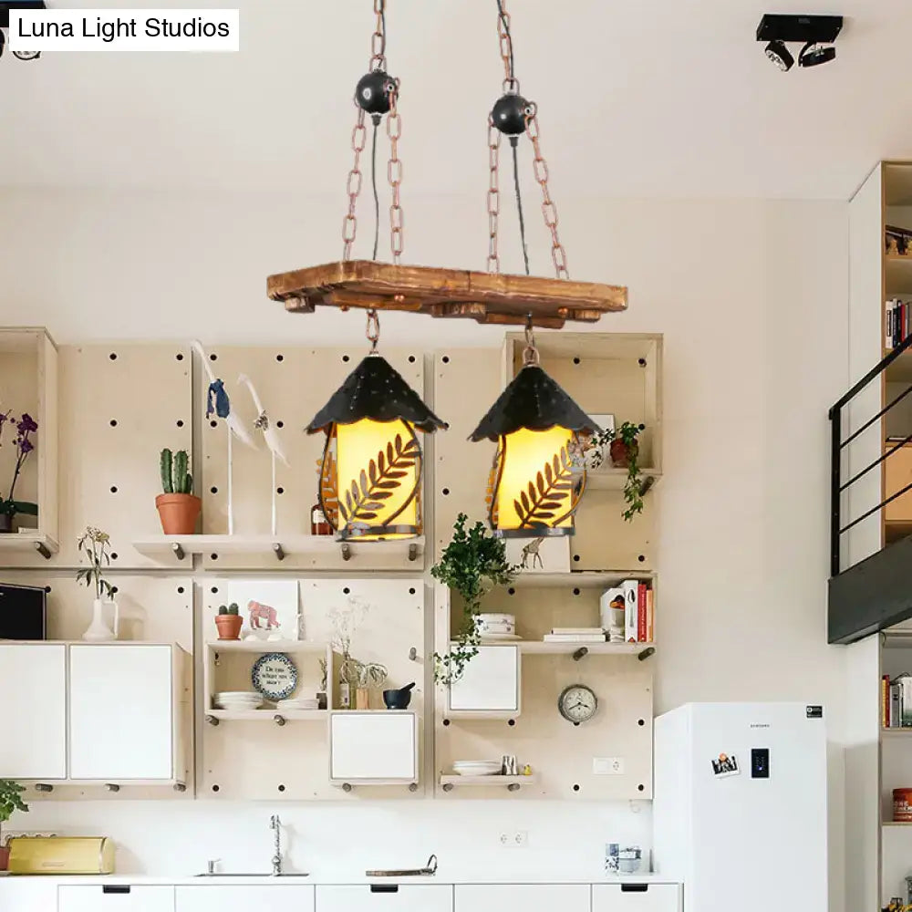 Rustic wooden beam pendant light with two black conical shades featuring leaf designs and warm yellow glass panels for industrial white clear lantern island lighting
