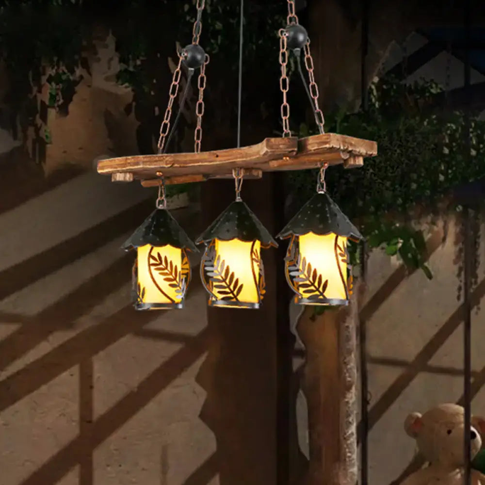 Rustic wooden beam suspending three industrial white clear lantern island lighting with black metal roofs and leaf etched panels