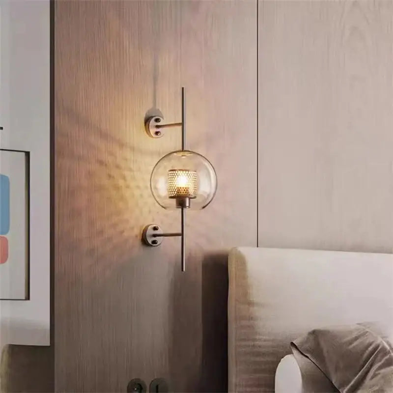 Modern brass-finished wall lamp with clear glass globe and intricate mesh-patterned bulb for decorbites industrial wind grid style