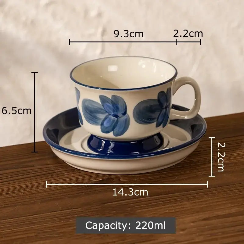 A white ceramic ink flowers cup and saucer set with blue floral hand-painted design and navy-blue rims for dining room decorbites