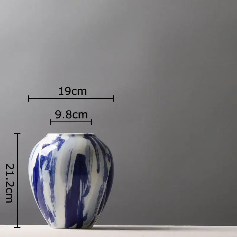 A ceramic vase with a glossy white base and bold ink style blue brushstroke flowers for living room decor
