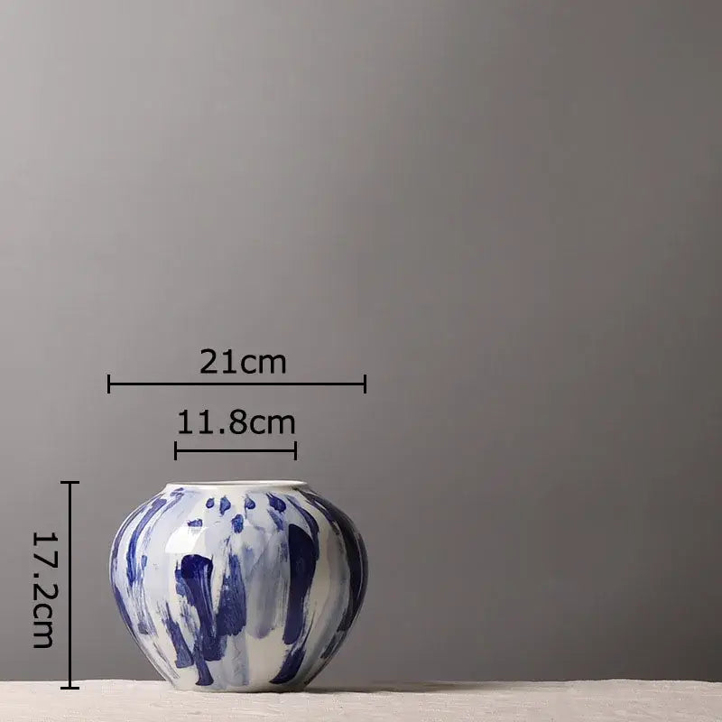 A round ceramic vase with a white base and ink style blue brushstroke flowers for living room decor