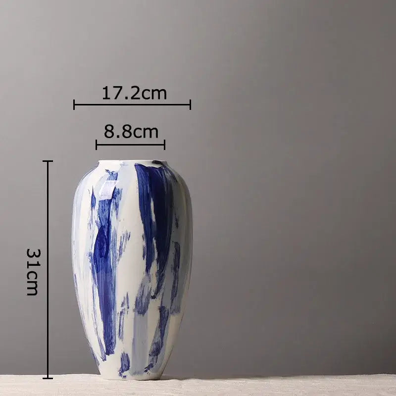 A sleek white ceramic vase with bold abstract blue brushstroke patterns in ink style flowers for living room decor