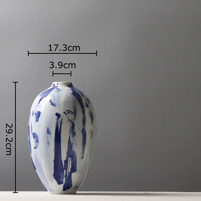A sleek hand-painted ceramic vase with bold blue ink style flowers on white base for living room decor
