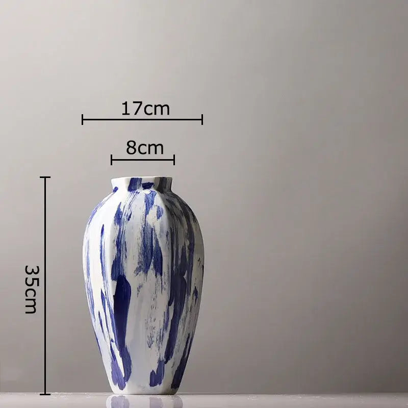 A tall slender ceramic vase with glossy white base and bold blue ink style brushstroke patterns for living room decor