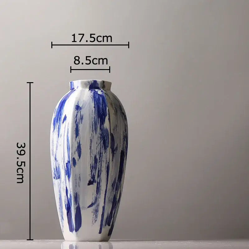 A tall slender ceramic vase with glossy white base and bold blue ink style brushstroke patterns for living room decor