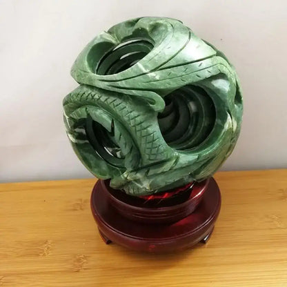 Intricate green jade stone dragon phoenix ball with detailed scales on a polished red wooden stand for living room decor