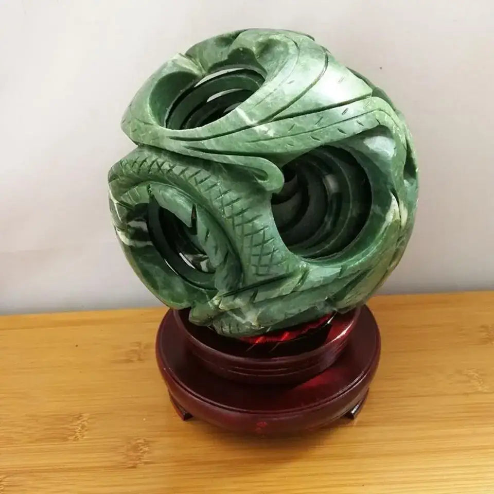Intricate green jade stone dragon phoenix ball with detailed scales on a polished red wooden stand for living room decor