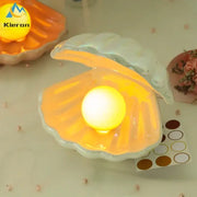 A glowing yellow pearl inside an iridescent ceramic shell led night light for bedroom illumination