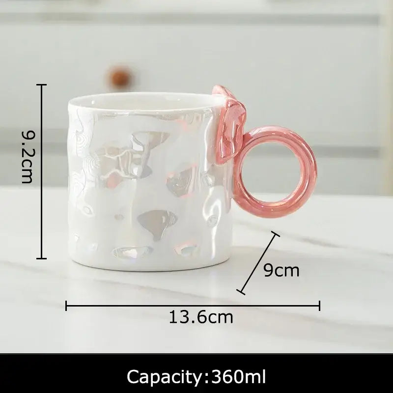 White ceramic coffee mug with textured iridescent bowknot glazed finish and distinctive pink ring handle decorbites bowknot glazed