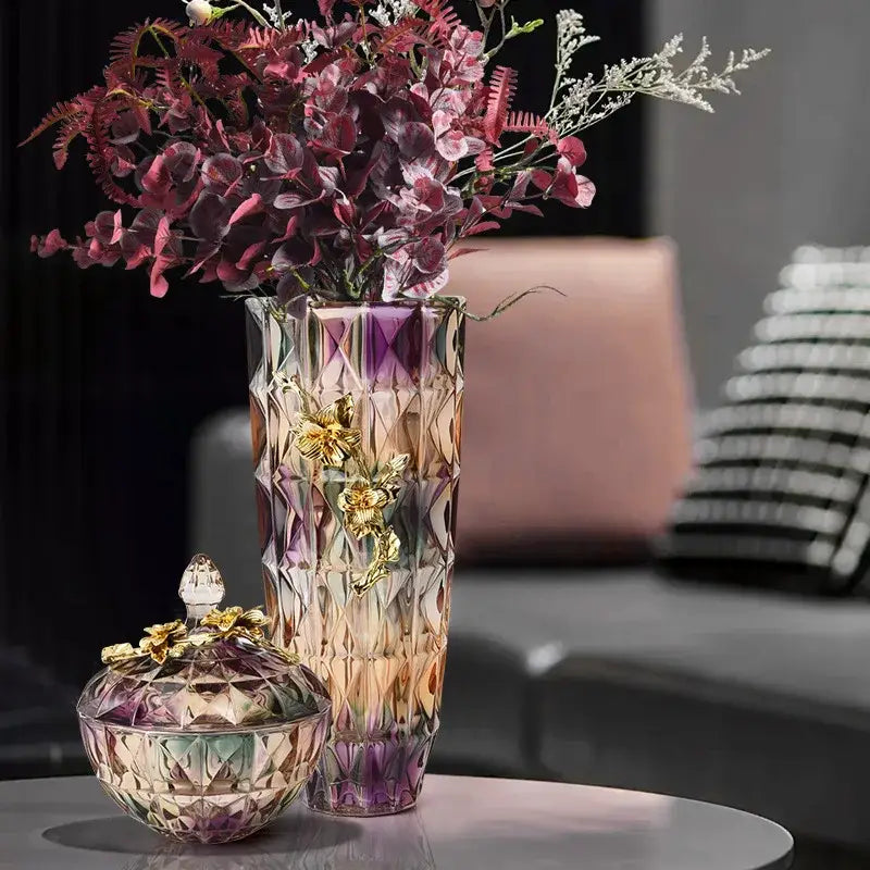 A tall faceted crystal glass vase with purple and gold gradient and golden floral embellishments for ornate display