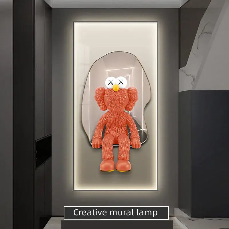 Orange kaws-style plush figure with white x-eyed face and yellow nose in sleek mirrored frame led wall lamp decor