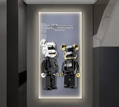 Two glossy black and silver be@rbrick figures with gold accents in an iron man metallic led wall lamp display frame