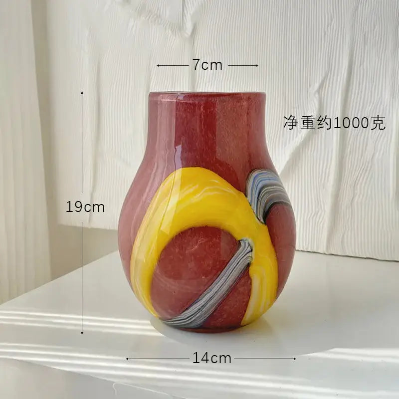 A vibrant hand-blown glass vase with an irregular geometric graffiti design in red, yellow, and gray for living room decor