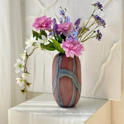 A blush pink glass vase with irregular geometric graffiti swirl patterns holds a vibrant floral bouquet for decorbites decor