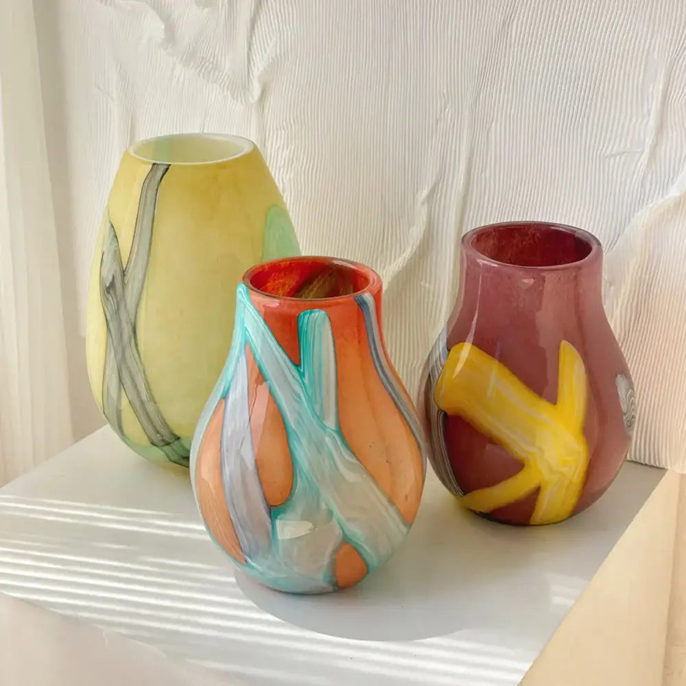 Three colorful hand-blown glass vases with irregular geometric graffiti patterns in vibrant hues for living room decor