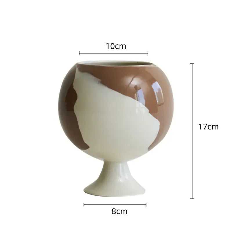 A glossy two-toned cream and brown ceramic irregular grain spherical vase with slender pedestal base for decorbites decor