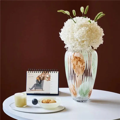 A tall irregular ribbed green and brown clear glass vase with textured swirls holds white hydrangeas for living room decorbites decor