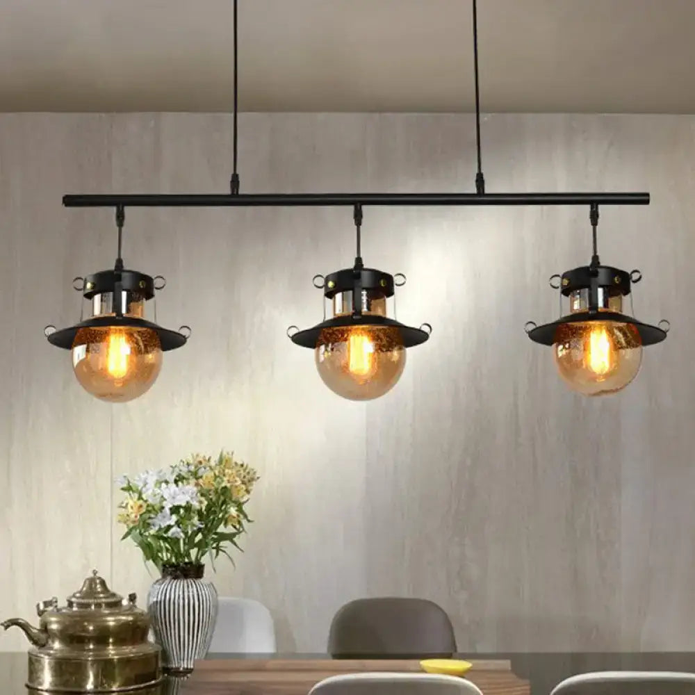 DecorBites 3-light linear island pendant with black metal frame and flared shade featuring amber globe shades