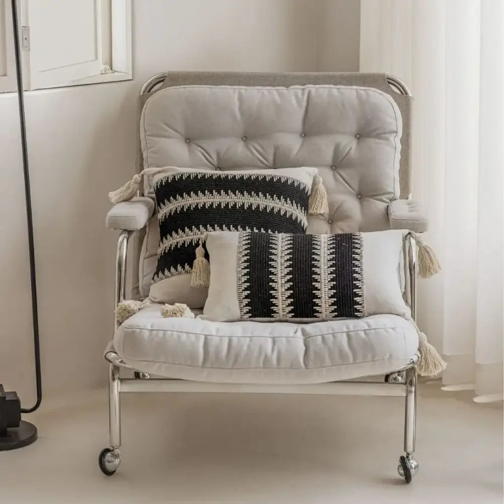 A sleek modern armchair with tufted beige upholstery and chrome legs complements decorbites jacquard crochet pillow covers