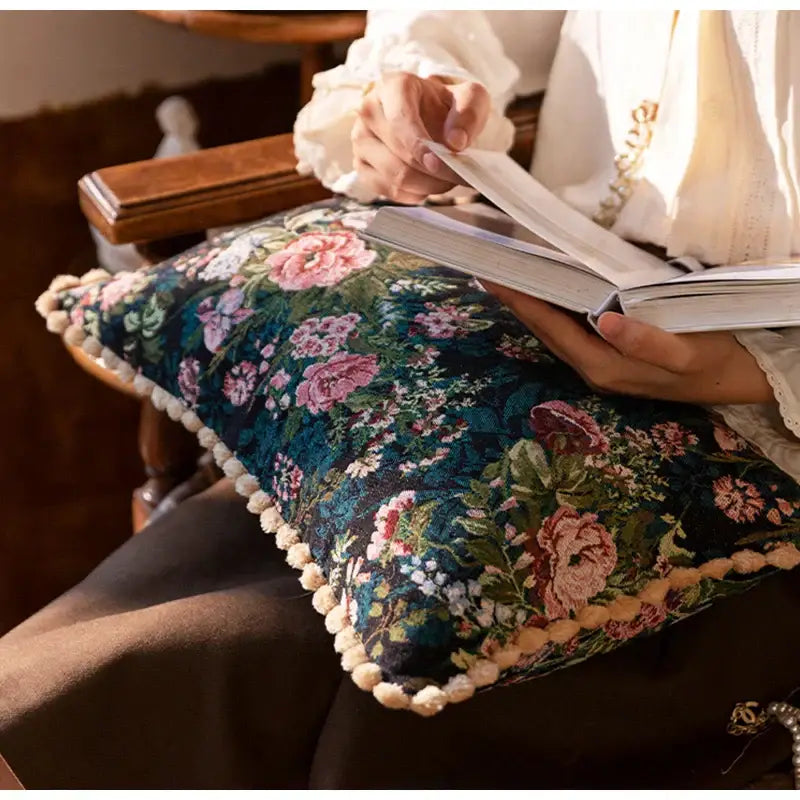 A plush dark teal jacquard farmhouse decor pillow case with floral pattern and cream pom-pom trim for living room